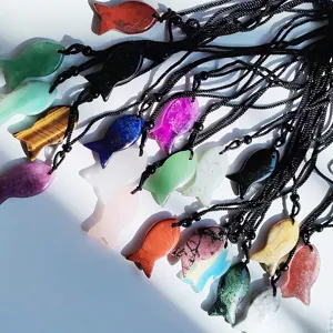 Close-up detail of assorted natural crystal fish pendants with black braided rope necklaces.