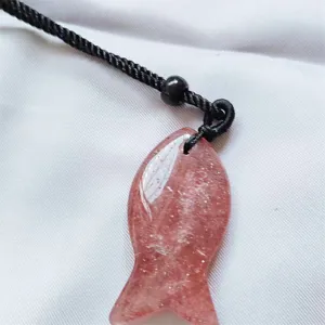 Close-up detail shot of the sparkling pink crystal fish pendant with black cord accessory.