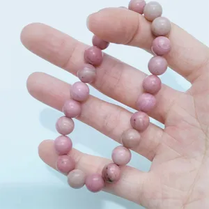 Natural stone pink beaded bracelet detail view, smooth polished gemstone single circle wrist jewelry.