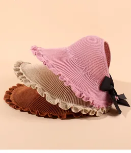 Close-up detail of stylish knit empty top sun hat with wide ruffle brim and black bow.
