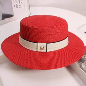 Close-up detail of the elegant red straw flat-top boater hat with a chic white ribbon and M charm.