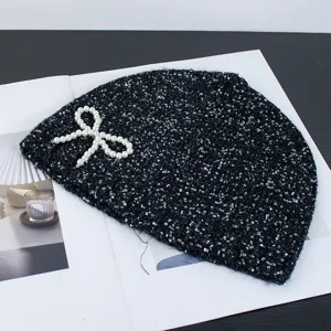 Black sequin knit beanie with elegant pearl bow, stylish winter warm hat fashion accessory.