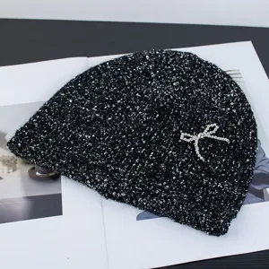 Black sequin knit beanie with a sparkling silver bow, cozy winter warm hat fashion accessory.