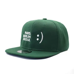 Detailed close-up view of dark green snapback baseball cap featuring stylish white embroidery.