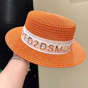 Vista dettagliata di un chic cappello di paglia arancione con nastro bianco e lettere dorate.