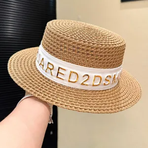 Cappello di paglia estivo con nastro bianco e decorazione di lettere metalliche per la spiaggia.