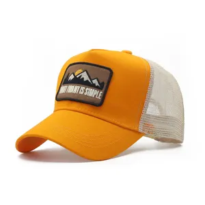 Vista dettagliata del cappellino trucker in rete arancione e beige con toppa da montagna.