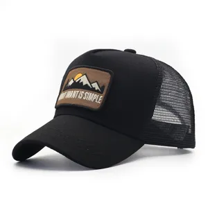 Primo piano dettagliato del cappellino trucker nero in mesh con una toppa da montagna.