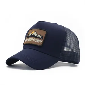 Vista dettagliata del berretto trucker blu scuro con stemma da montagna ricamato sulla parte.
