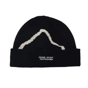 Detailed macro view of black winter knit beanie with white snow mountain silhouette.