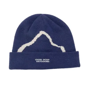 Close-up detail of blue knit beanie with white mountain pattern and outdoors text