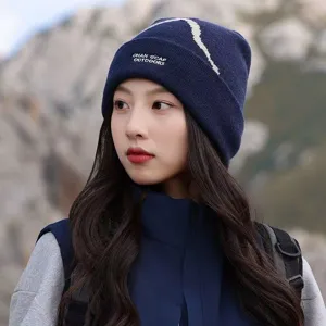 Detail view of a women's navy blue knitted beanie with outdoor embroidery in snowy mountains