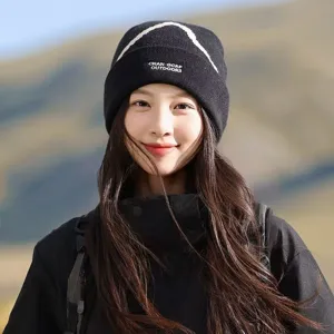Close-up of model wearing a black outdoor knitted beanie in a mountain setting