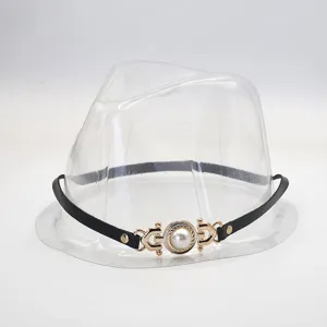 Close-up detail of a black leather hat band accessory featuring an elegant gold pearl buckle.