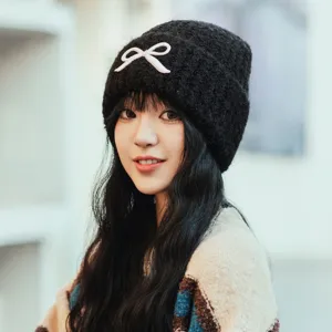 Women winter knit beanie hat with cute white bow, cozy warm knitted cap for cold weather fashion.