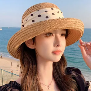 Détail d'un chapeau de paille pour femme avec un élégant ruban à pois blancs pour la plage