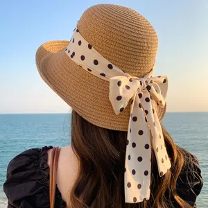 Détail d'un chapeau de paille montrant le ruban à pois sur un fond marin bleu