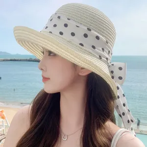 Vue détaillée d'un chapeau de paille pour femme avec ruban à pois sur fond de plage