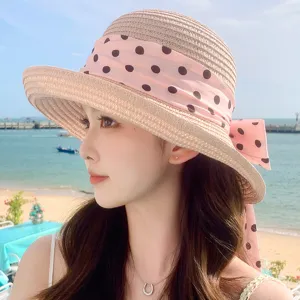 Vue latérale d'une femme portant un chapeau de paille à pois roses sur une plage d'été