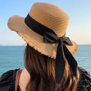 Detail shot of women summer straw sun hat featuring elegant black ribbon bow and fringe edge design.