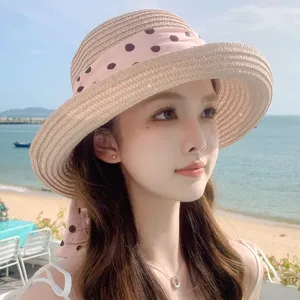Gros plan d'un chapeau de paille élégant avec ruban à pois sur un mannequin à la plage