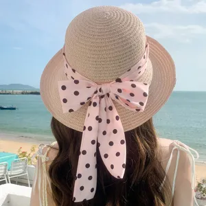 Vue arrière détaillée d'un chapeau de paille orné d'un grand nœud rose à pois