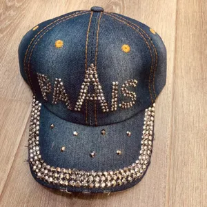 Gedetailleerd overzicht van de denim baseballpet met strass en sprankelende kristallen.