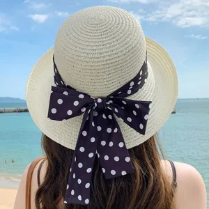 Vue arrière d'un chapeau de paille beige avec un grand nœud à pois à la plage