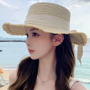 Close-up detail of stylish women's straw sun hat with ribbon and frayed brim for summer beach wear.