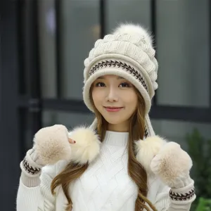 Detailed view of a woman wearing a cream knitted winter hat with matching fur gloves.