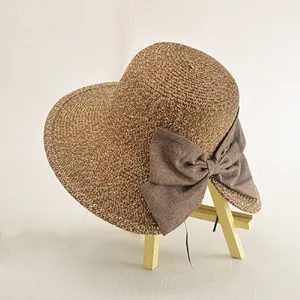 Close-up detail of a women summer brown straw sun hat featuring an elegant fabric bow.