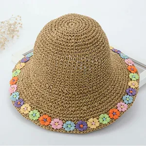 Primo piano del bordo del cappello di paglia estivo decorato con fiori all'uncinetto.
