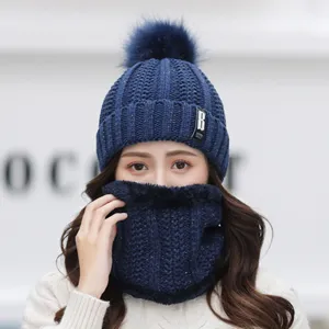 Close-up of women's warm winter knitted hat and fleece neck warmer set with cute pom pom.