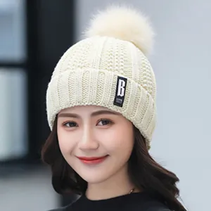 Winter warm knit beanie hat for women with cute pom pom and stylish letter patch detail.