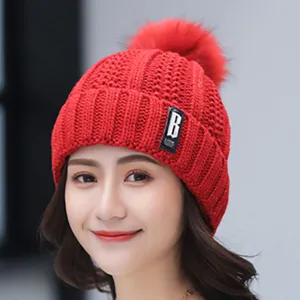 Close-up detail of the women's winter fleece lined red knit beanie hat with cute pom-pom.