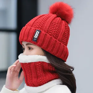 Side detail view of red knit winter beanie hat with fluffy pom pom and warm neck scarf.