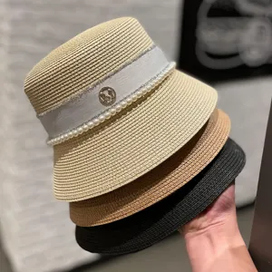 Summer women straw bucket hat with pearls and elegant ribbon, stylish sun protection beach cap.