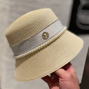 Summer women straw bucket hat with elegant white pearl ribbon and metal monogram detail stylish sun hat