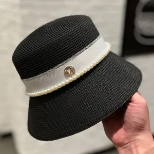 Detail shot of the black straw bucket hat featuring a white ribbon and pearl trim, elegant.