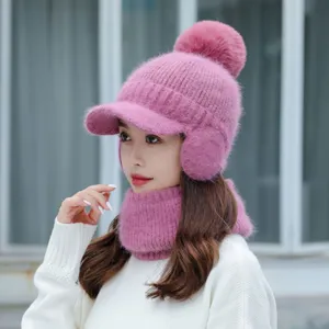 Primer plano detallado del acogedor gorro de invierno de punto rosa con orejeras y pompón.