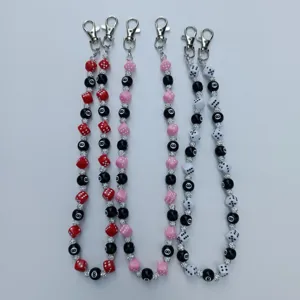 Close-up detail of acrylic dice and 8-ball bead chains with rhinestone spacers and metal clasps.