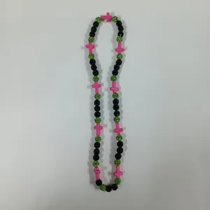 Detailed view of the colorful beaded necklace featuring black, green sparkle balls, pink cross charms.