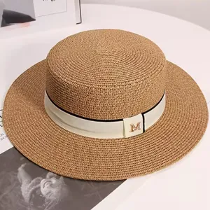 Stylish straw boater hat for women, featuring a chic ribbon and metal M charm for summer beach.