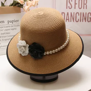 Chapeau de paille élégant avec chaîne de perles et décorations chics de camélias noir-blanc.