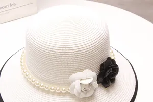 Chapeau de paille blanc élégant avec chaîne de perles et fleurs de camélia classiques.