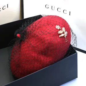 Detailaufnahme eines roten Wollbaretts mit elegantem schwarzem Netz und Blumendekor.