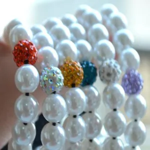 Nahaufnahme von weißen Perlen und bunten Strass-Shamballa-Akzenten für Schmuck