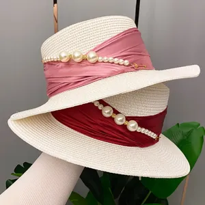Summer French elegant pearl flat-top straw hat detail, featuring delicate ribbon and pearl chains.