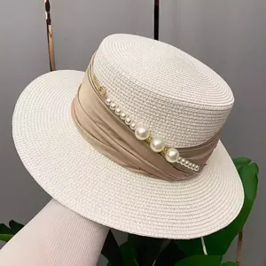 Close-up detail of summer flat top straw hat featuring pearl chain and ribbon decor.