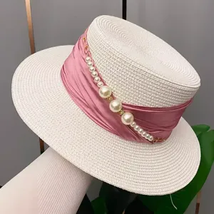 Detail shot of summer straw hat with pink ribbon and pearls, perfect for elegant sun protection.